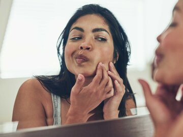 Frau drückt Pickel im Gesicht aus. | © Getty Images/PeopleImages