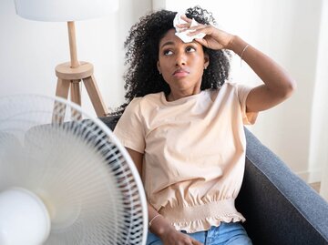 Person wischt sich Schweiß aus Gesicht vor Ventilator | © Getty Images/Paolo Cordoni