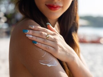 Nahaufnahme eine Frau cremt sich den Arm mit Sonnencreme ein | © GettyImages/Jackyenjoyphotography
