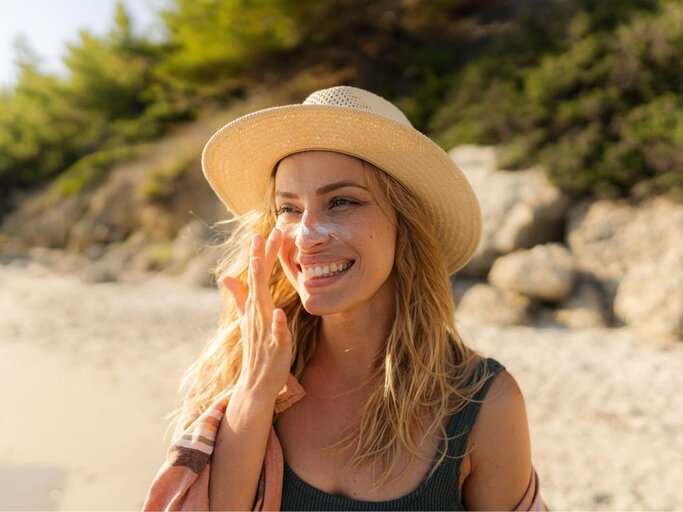 Person am Strand trägt Sonnencreme im Gesicht auf | © Getty Images/AleksandarNakic