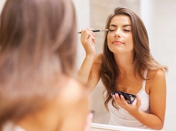 Junge Frau schminkt sich im Bad vor dem Spiegel | © Adobe Stock/gpointstudio