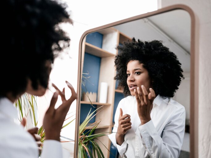Eine Frau bei der morgendlichen Skincare Routine vor dem Spiegel | © Getty Images / Westend61