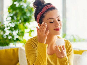 Frau mit sommerlichem Haarband trägt Creme auf | © gettyimages.de / Aja Koska