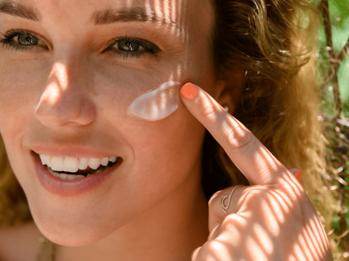 Frau trägt Sonnencreme im Gesicht auf | © Getty Images/Jamie Grill