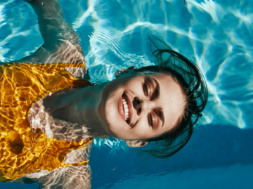 Frau schwimmt auf dem Rücken im Pool | © Getty Images/ShotPrime