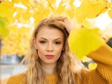 Blonde Frau unter gelben Herbst-Blättern | © Getty Images/Dennis Aglaster