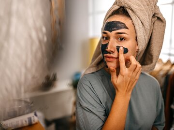 Frau trägt Heilerde Maske auf | © Getty Images/ mixetto