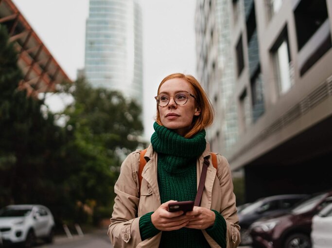 Rothaarige Frau vor Wolkenkratzer | © Getty Images/Halfpoint Images