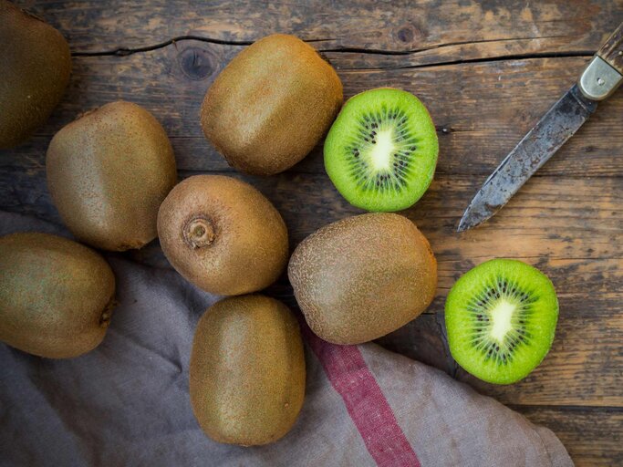 Kiwis auf einem Brett mit einem Messer daneben | © Getty Images/Westend61