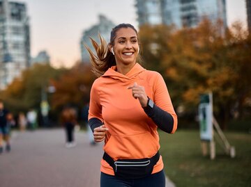 Frau lächelt während sie joggt und Musik hört | © Getty Images/Drazen Zigic
