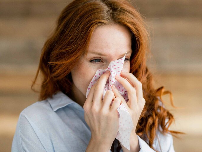 Frau mit roten Haaren putzt sich die Nase | © Getty Images/Westend61