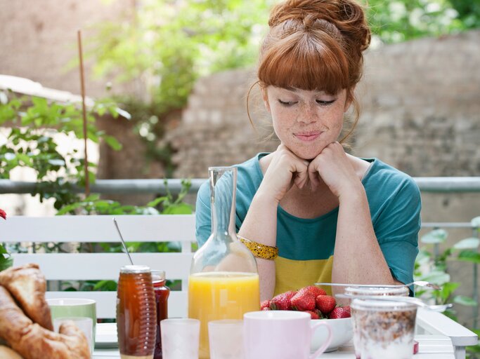 Eine junge Frau schaut skeptisch auf ihr Frühstück herab | © GettyImages/Westend61