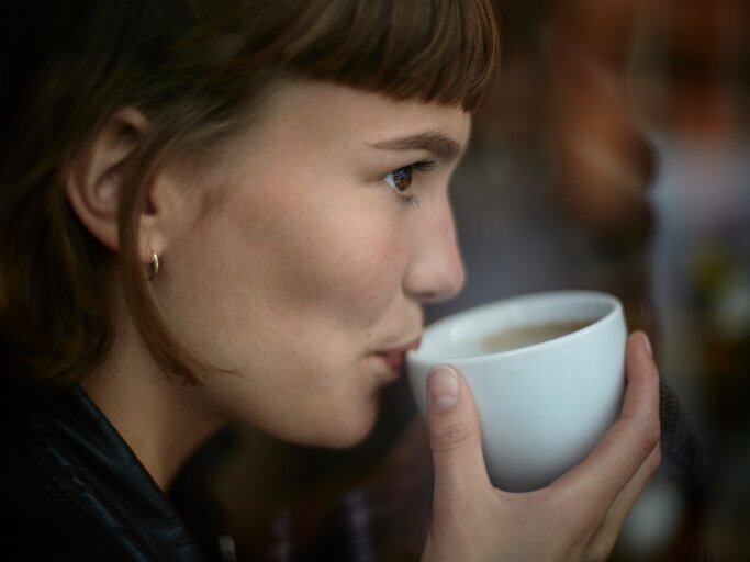 Eine junge Frau trinkt Kaffee | © GettyImages/Oliver Rossi