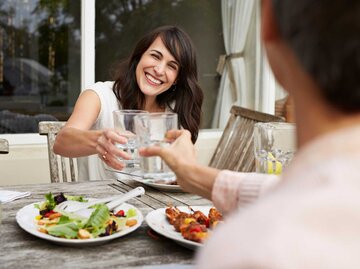 Mann und Frau stoßen gemeinsam beim Essen an | © Getty Images/Klaus Vedfelt