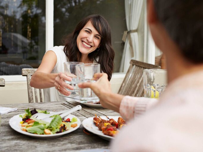 Mann und Frau stoßen gemeinsam beim Essen an | © Getty Images/Klaus Vedfelt