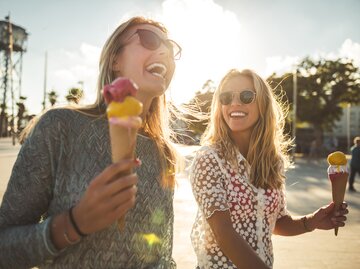 Zwei Frauen genießen ihr Eis in der Sonne | © GettyImages/Georgijevic