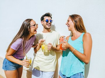 Zwei Frauen und ein Mann halten erfrischende isotonische Getränke | © GettyImages/Westend61