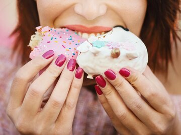 Person beißt in Donut | © Getty Images/Aja Koska