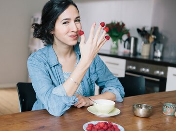 Eine Frau hat Himbeeren auf ihre Finger gesteckt | © GettyImages/Halfdark