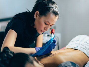 Person tätowiert Rücken von anderer | © Getty images/martin-dm