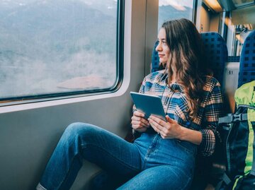 Frau fährt mit dem Zug und schaut aus dem Fenster | © Getty Images/martin-dm