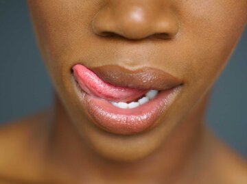 Dunkelhäutige Frau fährt sich mit der Zunge über die Lippen | © Getty Images/Karin Dreyer