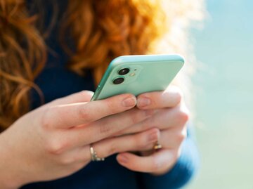 Nahaufnahme einer rothaarigen Frau, die ihr Handy benutzt | © Getty Images/Tim Robberts