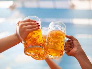  Erhöhter Bierkrug beim Anstoßen auf dem Oktoberfest | © Adobe Stock/tiagozr