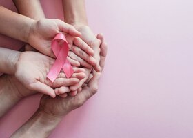 Hände von oben fotografiert, die eine pinke Schleife halten