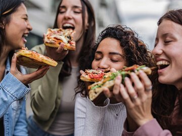 Gruppe von jungen Frauen isst Pizza. | © Adobe Stock/PintoArt
