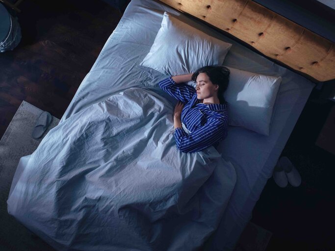 Frau liegt im Bett vom Fenster kommt leichtes Licht ins Zimmer | © Getty Images/gorodenkoff