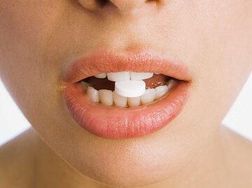 Lippen mit einer Pille zwischen den Zähnen | © Getty Images/Martin Barraud