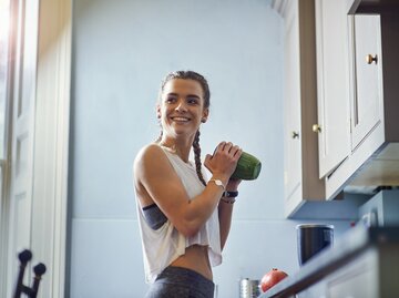 Junge Frau in Sportklamotten mit Shaker in der Küche | © gettyimages.de | Matt Lincoln