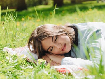 Frau liegt im Gras und schläft | © gettyimages.de / ALotOfPeople