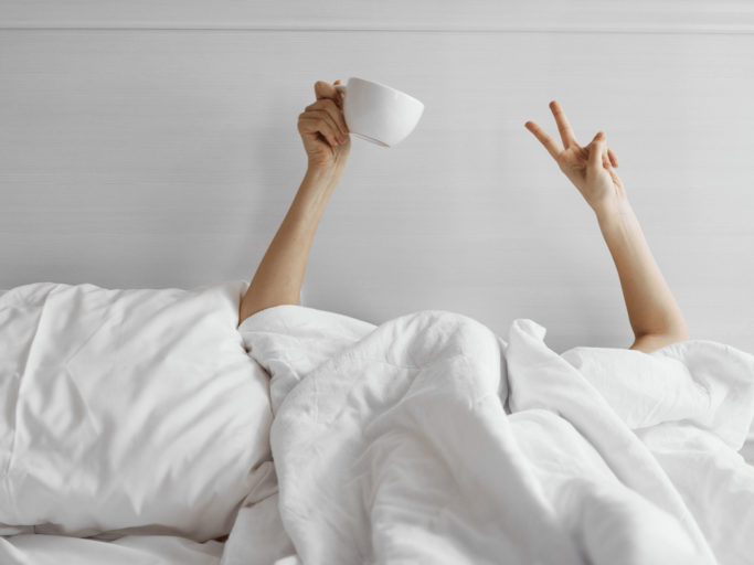 Frau mit Kaffeetasse im Bett | © Getty Images/ShotPrime