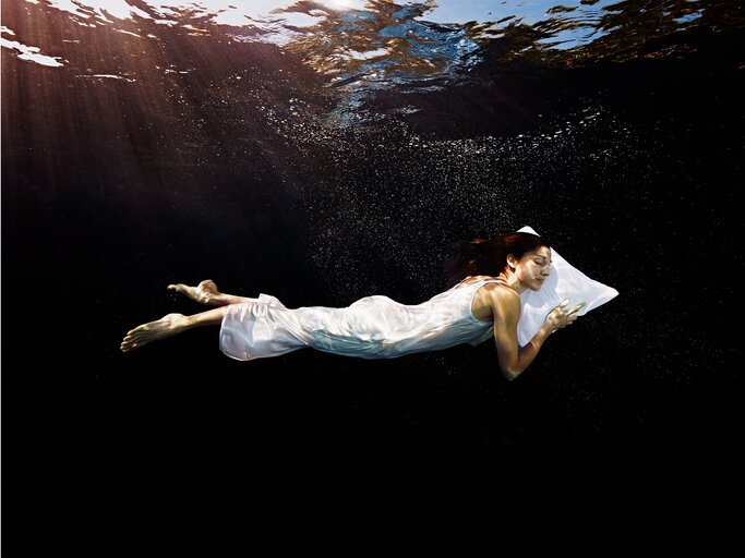 Frau schläft auf dem Bauch im Wasser | © Getty Images/Thomas Barwick