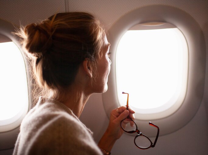 Frau hat das Gesicht zum Flugzeugfenster gedreht | © Getty Images/Kathrin Ziegler