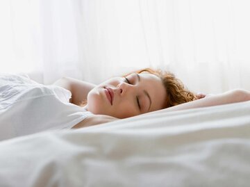 Frau schläft im Bett | © Getty Images/Jose Luis Pelaez