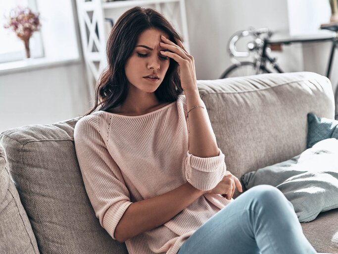 Gestresste Frau sitzt auf Couch | © Getty Images/g-stockstudio