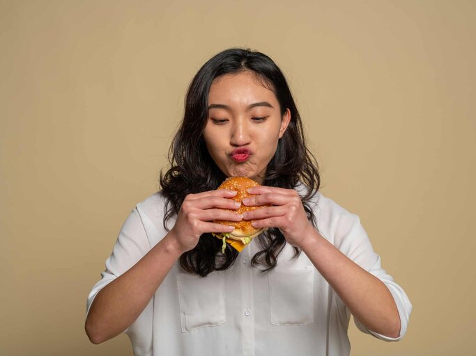 Frau mit Burger in der Hand | © Getty Images/MOAimage