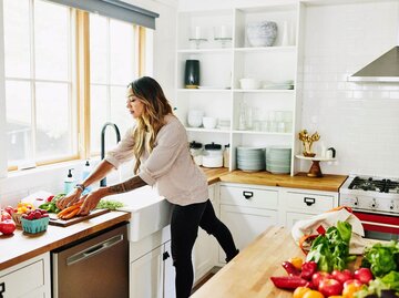 Frau beim Kochen in der Küche | © Getty Images/Thomas Barwick