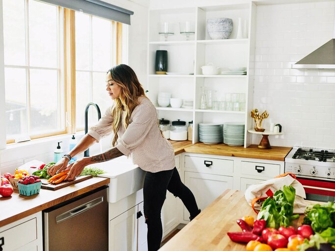 Frau beim Kochen in der Küche | © Getty Images/Thomas Barwick