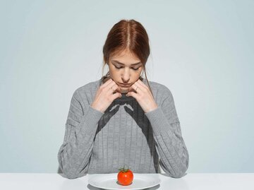 Frau sitzt deprimiert vor fast leerem Teller | © Getty Images/Francesco Carta fotografo