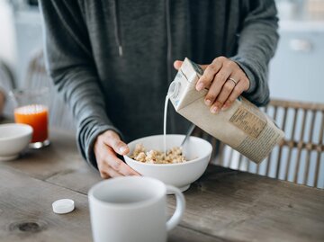 Frau gießt Pflanzenmilch in eine Schale mit Müsli | © Getty Images/AsiaVision