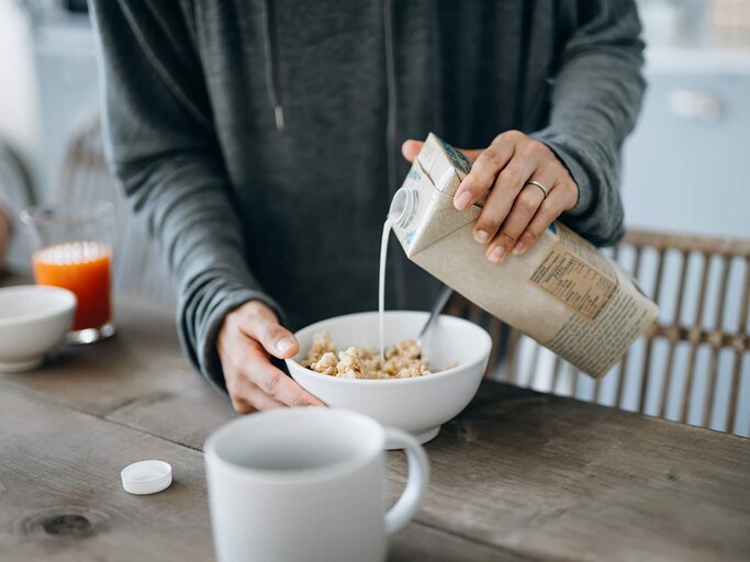 Frau gießt Pflanzenmilch in eine Schale mit Müsli | © Getty Images/AsiaVision