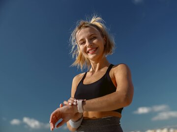 Junge blonde Frau mit Uhr am Handgelenk lacht in die Kamera | © Getty Images/Creative Credit