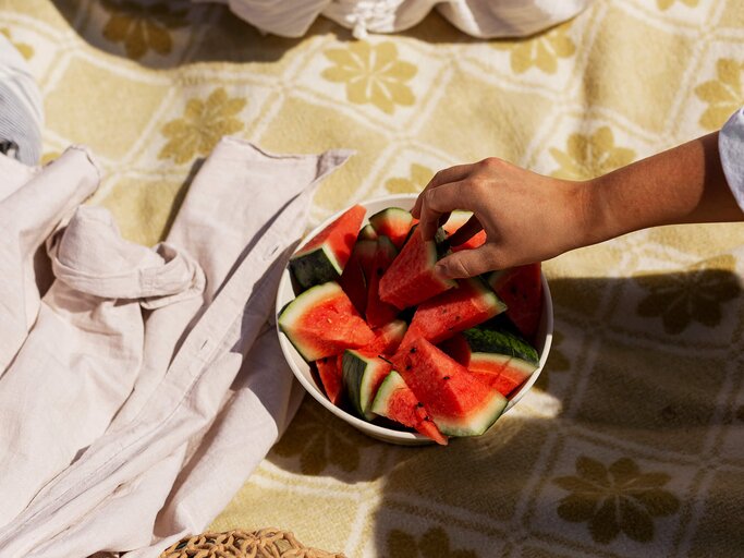 Hand greift nach einer Schale voller Wassermelonen-Stücke | © Getty Images/Johner Images