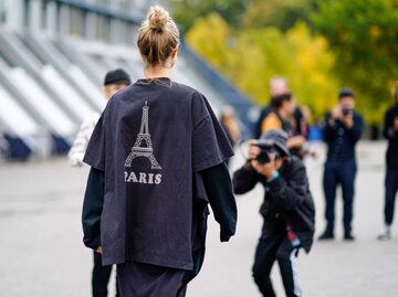 Frau trägt schwarzes Shirt mit Eiffelturm-Logo und Paris-Schriftzug | © Getty Images/Edward Berthelot