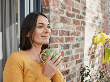 Frau mit Tasse auf Terrasse | © Getty Images/Westend61