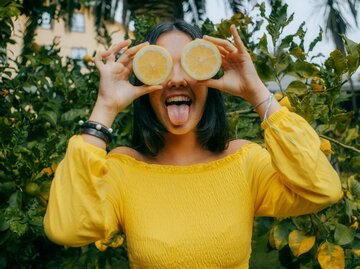 Frau hält sich zwei Zitronen vor die Augen und streckt die Zunge raus | © Getty Images/Carol Yepes